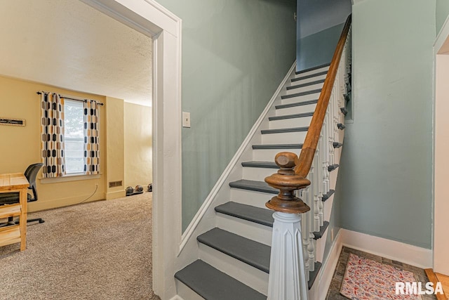 stairway with carpet and a textured ceiling