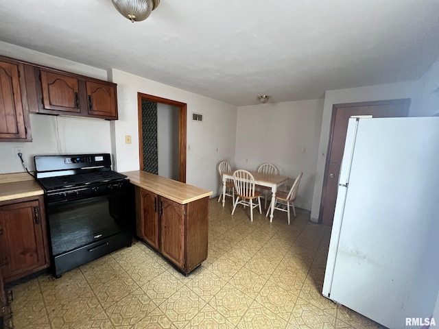 kitchen with kitchen peninsula, black gas stove, white fridge, and dark brown cabinets