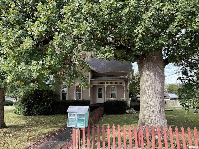 view of front of home with a front lawn, roof with shingles, and fence