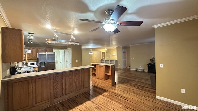 kitchen with stainless steel fridge with ice dispenser, ornamental molding, kitchen peninsula, a textured ceiling, and hardwood / wood-style flooring