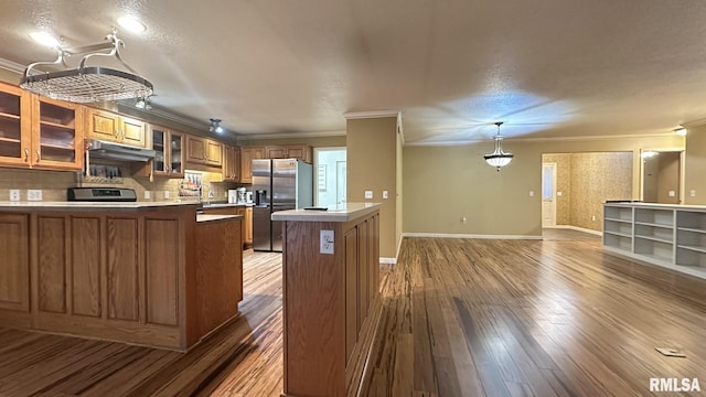 kitchen with sink, crown molding, hanging light fixtures, stainless steel fridge, and wood-type flooring