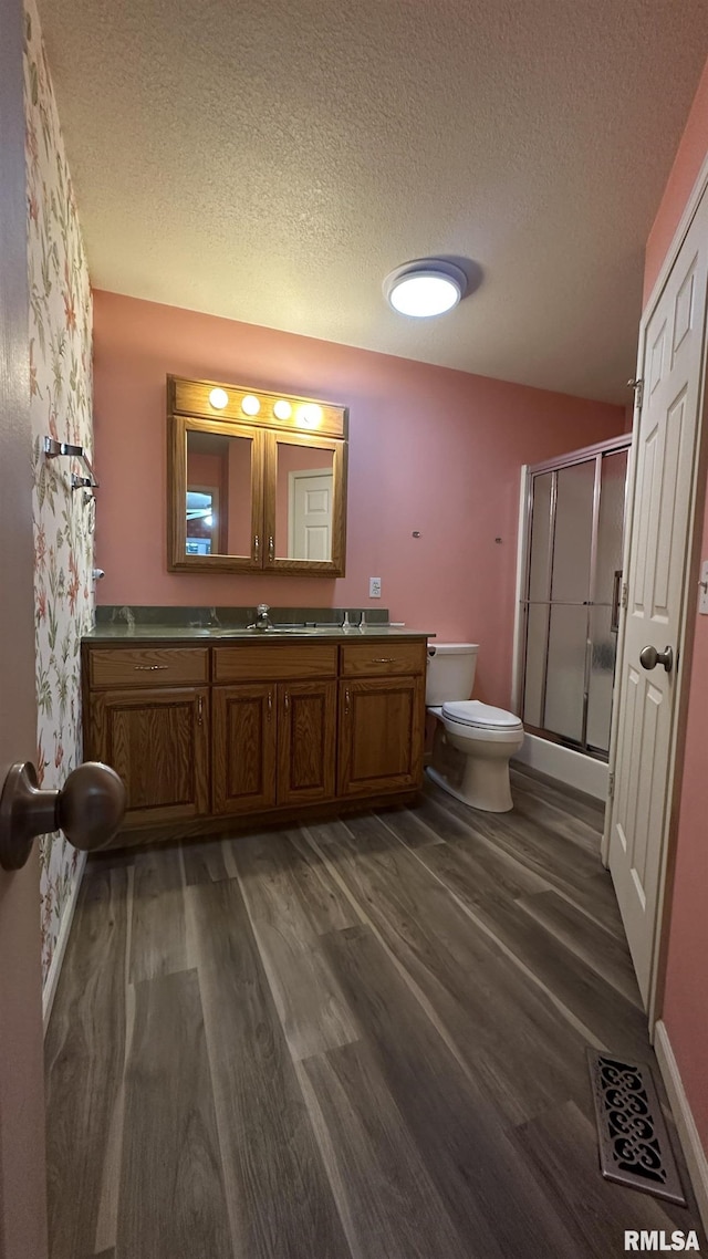 bathroom with hardwood / wood-style floors, vanity, a textured ceiling, and a shower with door