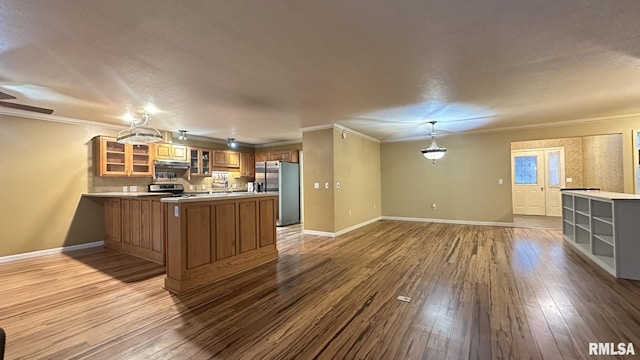 kitchen featuring crown molding, appliances with stainless steel finishes, decorative light fixtures, light hardwood / wood-style floors, and kitchen peninsula