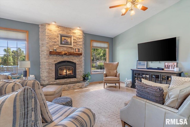 living room featuring ceiling fan, a stone fireplace, tile patterned flooring, and vaulted ceiling