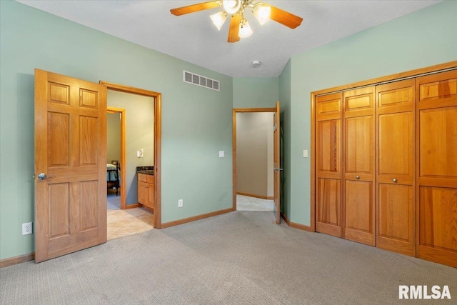 unfurnished bedroom featuring light carpet, ceiling fan, ensuite bath, and a closet