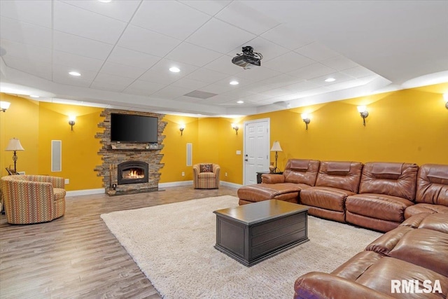 living room with a fireplace, light wood-type flooring, and a raised ceiling