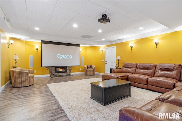 home theater room featuring a stone fireplace and light hardwood / wood-style floors