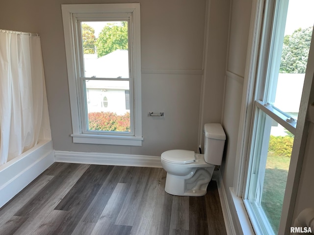 bathroom featuring hardwood / wood-style flooring, shower / bath combo with shower curtain, and toilet