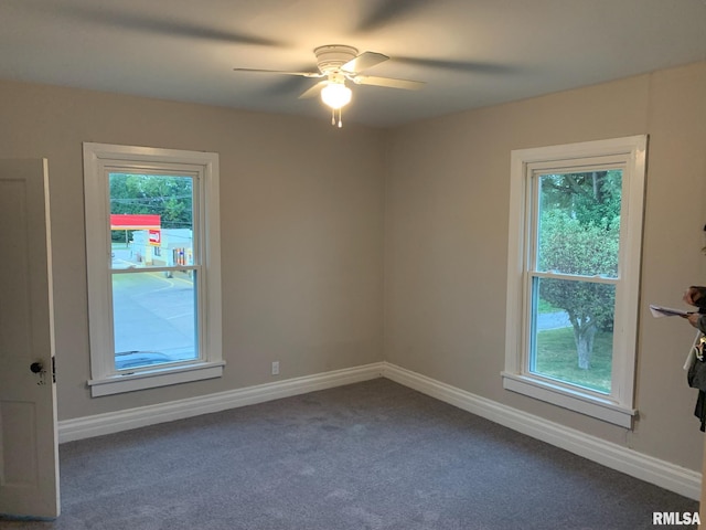 empty room with dark colored carpet, plenty of natural light, and ceiling fan