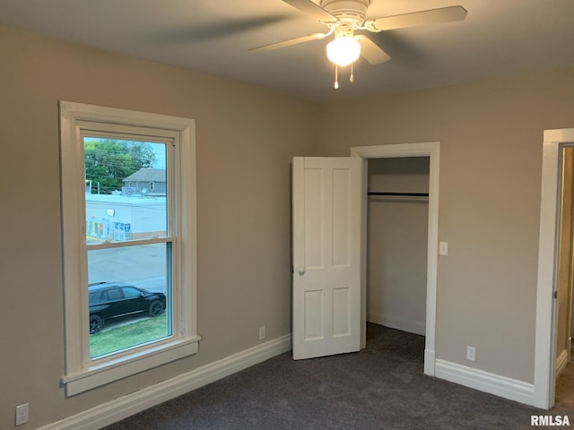 unfurnished bedroom featuring a closet, dark carpet, and ceiling fan