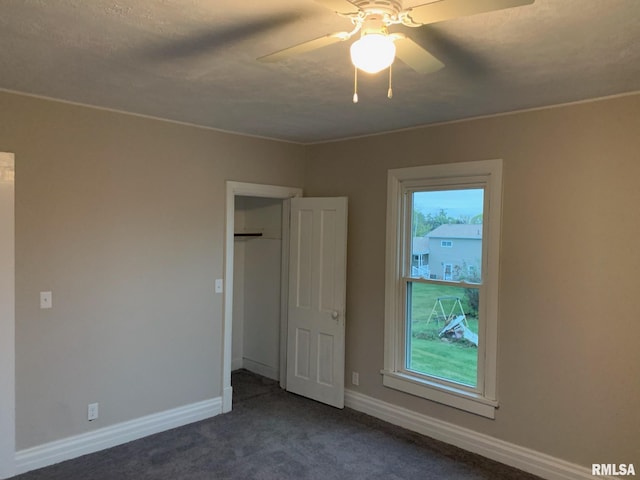 unfurnished bedroom featuring dark colored carpet and ceiling fan