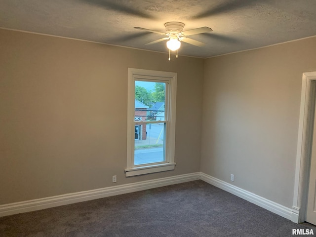 unfurnished room featuring ceiling fan, dark carpet, and a textured ceiling