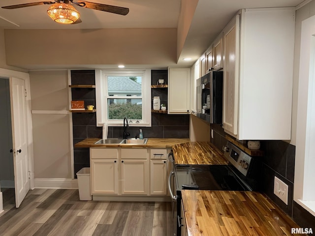 kitchen with butcher block counters, range with electric cooktop, sink, and white cabinets