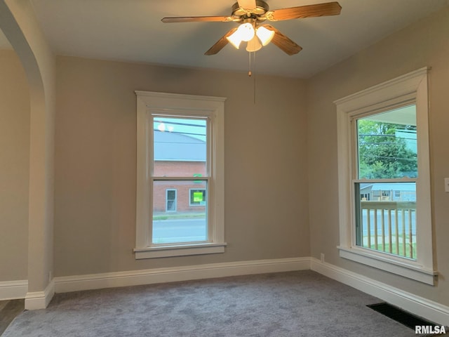 empty room with plenty of natural light, ceiling fan, and carpet floors