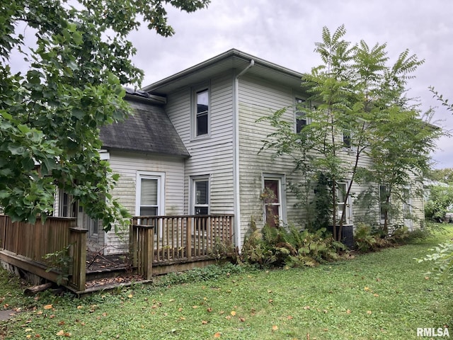 back of property with a wooden deck and a lawn