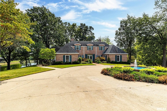 view of front of property with a water view and a front lawn