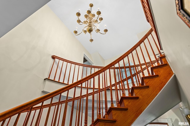 stairs with high vaulted ceiling and a chandelier