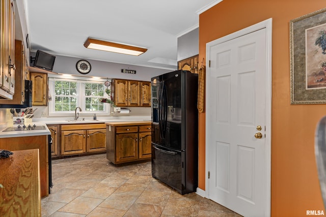 kitchen featuring crown molding, black refrigerator with ice dispenser, and sink