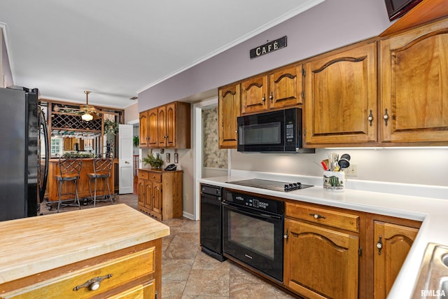 kitchen with black appliances, crown molding, and wood counters