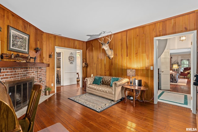 living room with ornamental molding, a fireplace, wood walls, and hardwood / wood-style floors