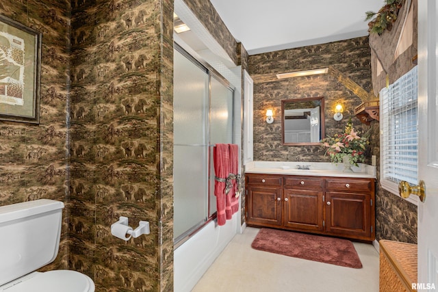 full bathroom with shower / bath combination with glass door, tile walls, vanity, and toilet