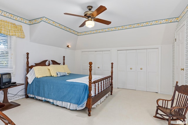 bedroom featuring ceiling fan, lofted ceiling, two closets, and carpet