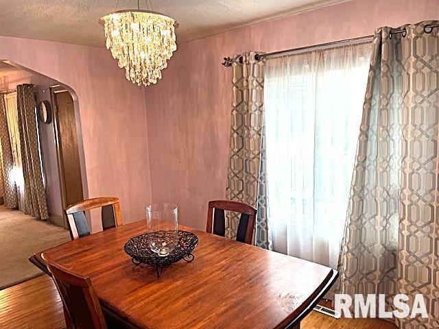 dining area featuring a chandelier, a textured ceiling, and light hardwood / wood-style floors