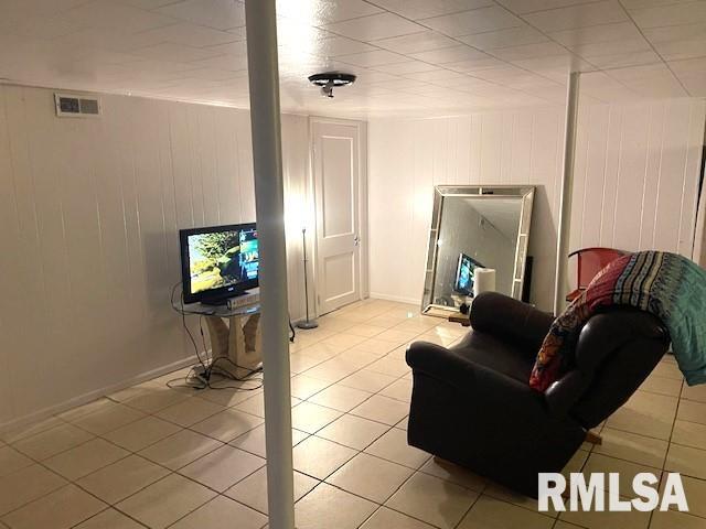 living room with wood walls and light tile patterned floors