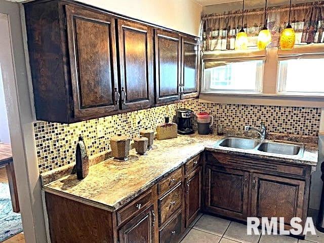 kitchen with backsplash, dark brown cabinets, sink, and decorative light fixtures