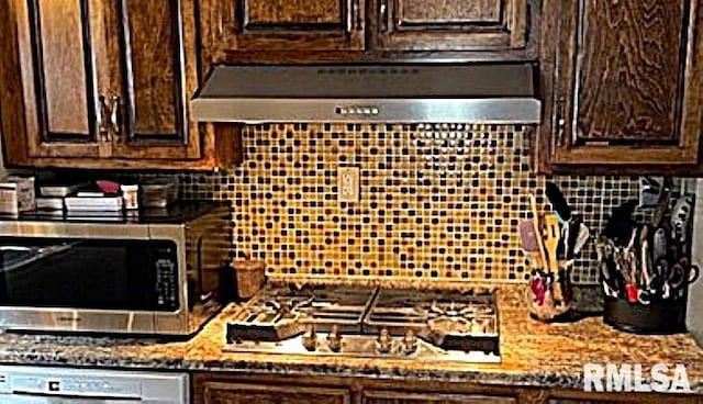 kitchen with decorative backsplash, dark brown cabinets, stainless steel appliances, and range hood