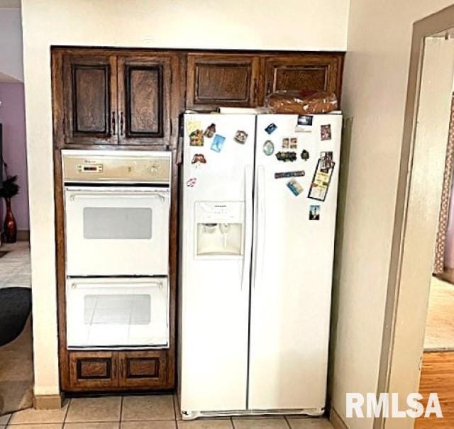 kitchen with dark brown cabinets, light tile patterned floors, and white appliances