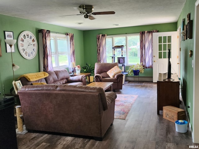 living room featuring ceiling fan, a textured ceiling, baseboard heating, and dark wood-type flooring