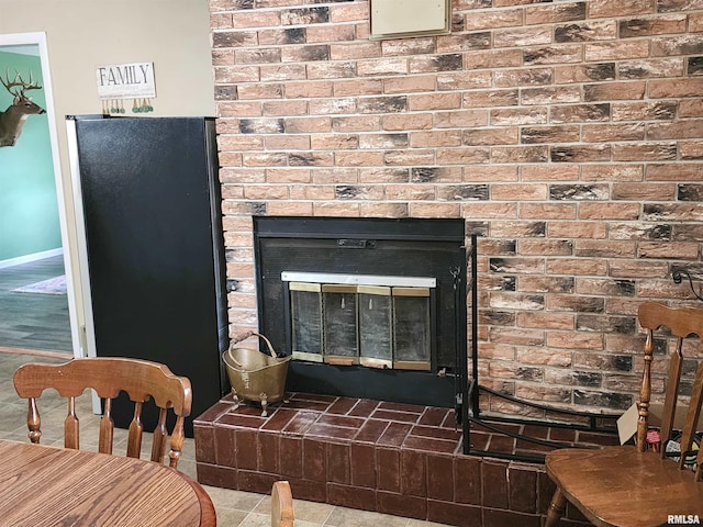 interior details featuring a fireplace, black refrigerator, and tile patterned floors