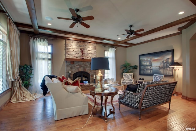 living room featuring a stone fireplace, light wood-type flooring, and a wealth of natural light