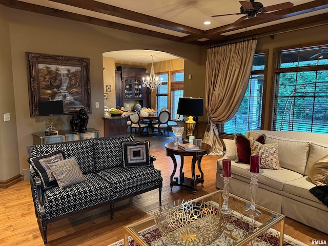 living room featuring ceiling fan with notable chandelier, wood-type flooring, and beam ceiling