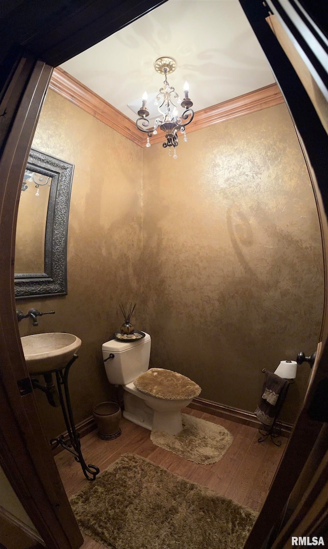 bathroom with hardwood / wood-style flooring, sink, a notable chandelier, ornamental molding, and toilet