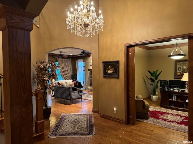 hall with an inviting chandelier, a towering ceiling, and hardwood / wood-style floors