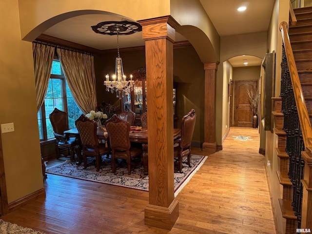 dining room featuring ornamental molding, light wood-type flooring, a chandelier, and ornate columns