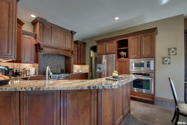 kitchen with light stone counters, kitchen peninsula, appliances with stainless steel finishes, and tasteful backsplash