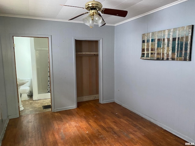 unfurnished bedroom featuring connected bathroom, hardwood / wood-style flooring, ceiling fan, crown molding, and a closet