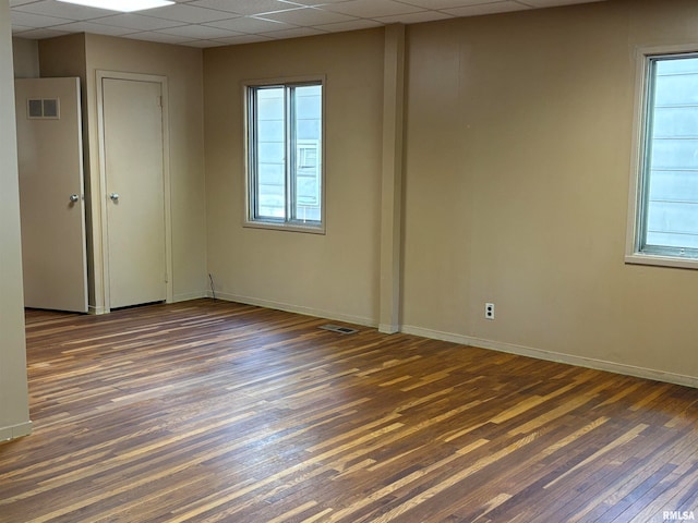 empty room with dark wood-type flooring and a paneled ceiling