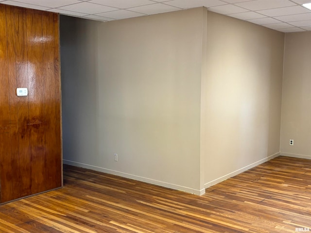 empty room with a paneled ceiling and wood-type flooring