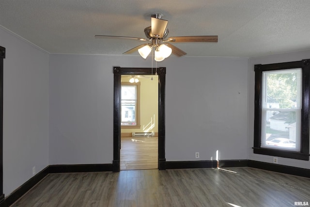 unfurnished room with a textured ceiling, ceiling fan, plenty of natural light, and dark hardwood / wood-style flooring