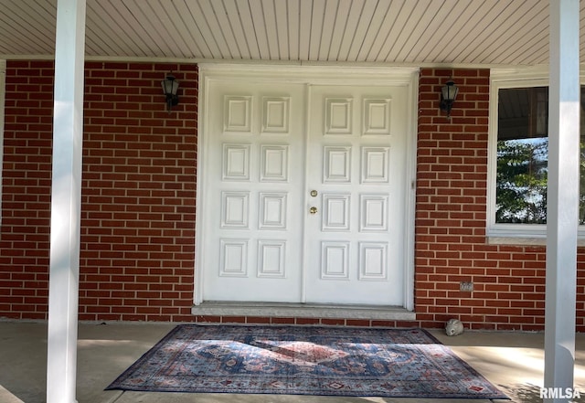 entrance to property featuring brick siding and covered porch