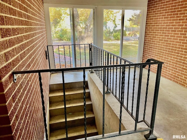 staircase featuring brick wall and concrete floors