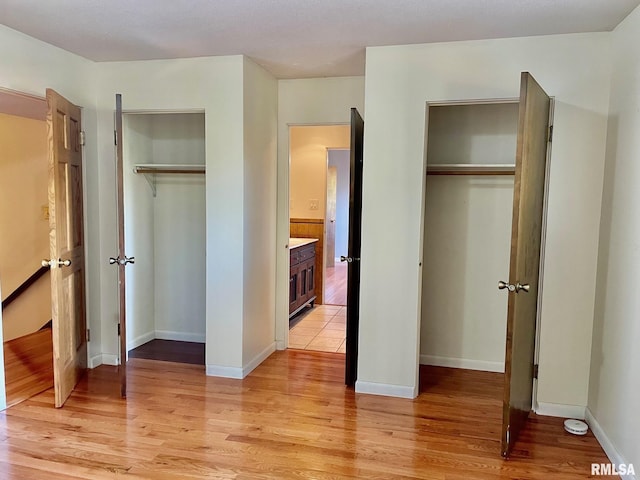 bedroom with two closets and light hardwood / wood-style flooring