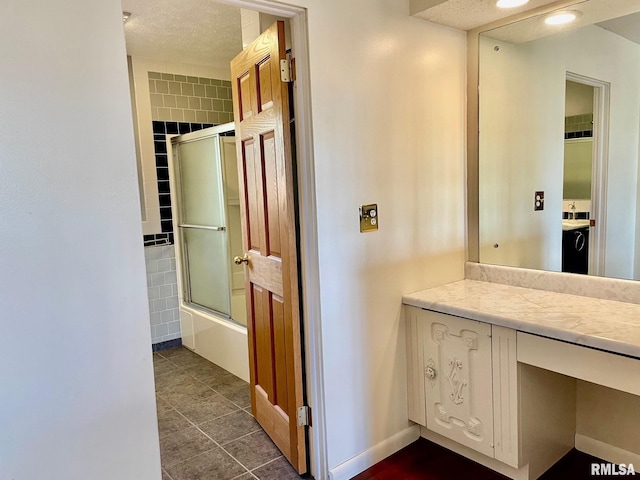 bathroom with vanity, tile patterned flooring, a textured ceiling, and combined bath / shower with glass door