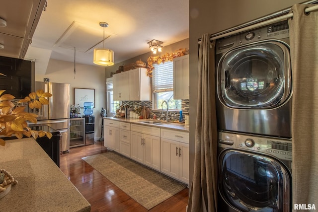 washroom featuring wine cooler, sink, dark wood-type flooring, and stacked washer / drying machine