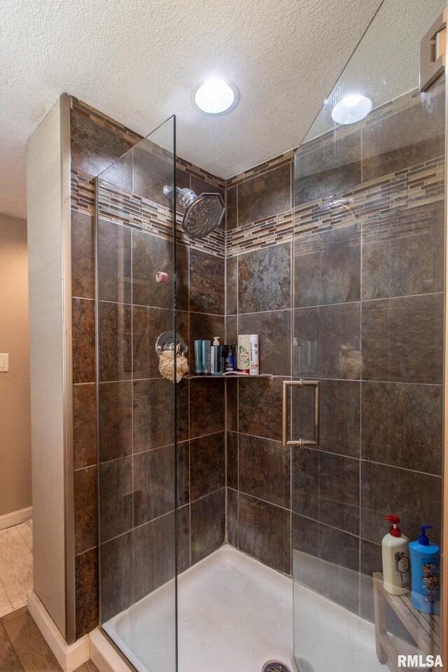 bathroom with a textured ceiling, an enclosed shower, and tile patterned floors