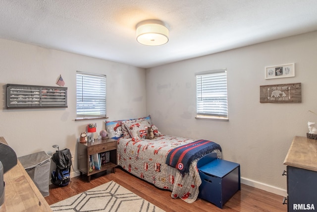 bedroom with a textured ceiling, dark hardwood / wood-style floors, and multiple windows